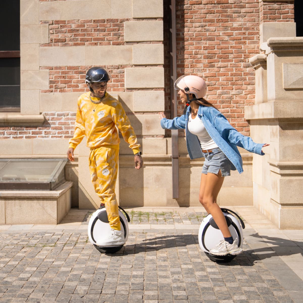 Two helmeted riders demonstrating INMOTION E20 electric wheels