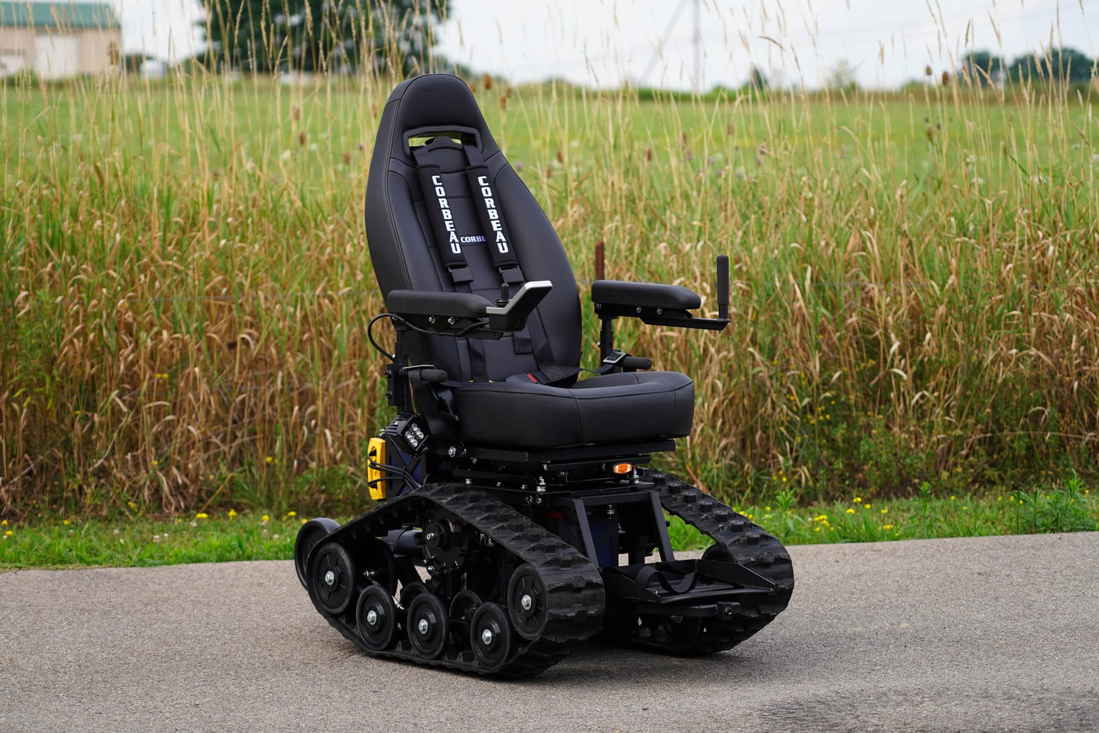 TracFab tracked wheelchair outdoors beside tall grass